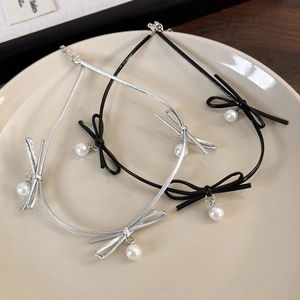 Détail de colliers choker à nœuds noir et blanc avec perles nacrées sur une assiette