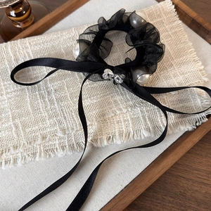 Detail of black mesh scrunchie with pearls, ribbon bow and heart crystal on a tray