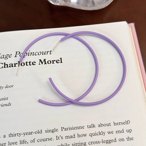 Dettaglio di orecchini a cerchio viola opaco su uno sfondo di libro vintage