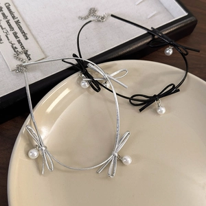 Détail de chokers à nœud papillon et perles en argent et noir sur une assiette