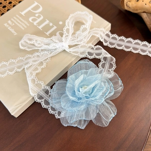 Close-up of a blue organza camellia flower on a delicate white lace ribbon choker