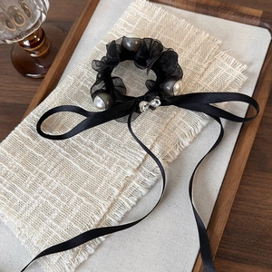 Detail of black tulle scrunchie with white pearls and long satin ribbon bow with rhinestone