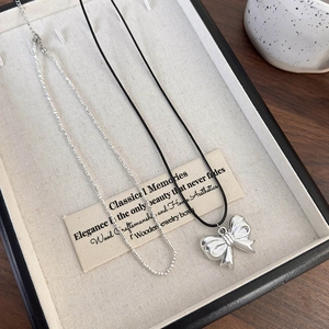 Macro detail of a silver bow necklace and beaded chain on a classic wooden box