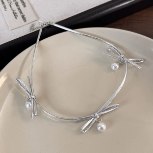 Détail du collier choker nœud argenté avec perles de culture sur plateau blanc
