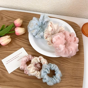 Texture détaillée des chouchous à fleurs en résille en bleu, crème et rose pastel