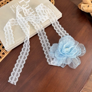 Detail of white lace choker with a large light blue organza flower and pearl center