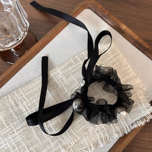 Detail of elegant black mesh hair scrunchie with white pearls and long silk ribbons