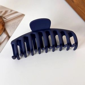 Detail view of large matte navy blue shark hair claw clip on minimalist background