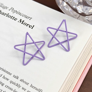 Dettaglio di orecchini a forma di stella viola opaco su una pagina di libro aperta