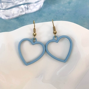 Eleganti orecchini a cuore vuoto blu opaco con ganci dorati su vassoio di ceramica