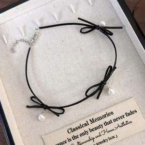 Détail d'un collier ras du cou à nœuds noirs avec perles et fermoir en argent ajustable