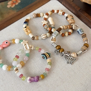 Bracciali fatti a mano con perle, ciondoli animali in ceramica e conchiglie su tessuto
