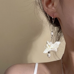 Elegant shell flower earrings with silver chain and pearls worn by a model in soft light
