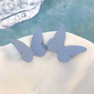 Eleganti orecchini a farfalla blu opaco presentati su un piatto in ceramica bianca