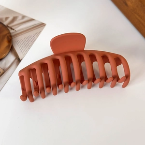 Close-up of a large matte orange shark hair claw clip on an aesthetic lifestyle background