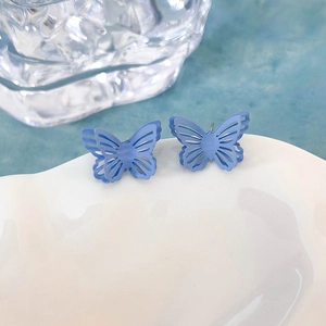 Dettaglio di orecchini a farfalla blu opaco su un vassoio di ceramica bianca