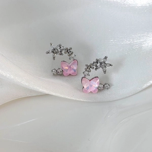 Macro shot of pink resin butterfly earrings with star and flower crystal details on silk