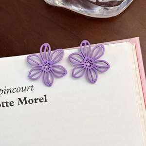 Vista dettagliata di orecchini a fiore viola su un libro con design a petali minimalista