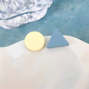 Vista macro di orecchini geometrici opachi con cerchio giallo e triangolo blu