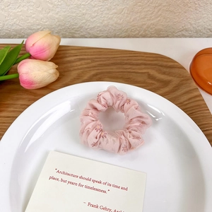 Gros plan détaillé du chouchou en maille fleurie rose avec une texture de tulle délicate