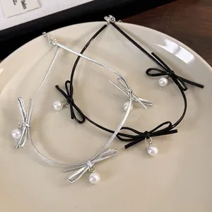 Collier ras de cou élégant avec nœuds et perles sur une assiette en céramique blanche