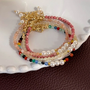 Close-up of multilayer beaded bracelet with pink crystals and pearls on white plate