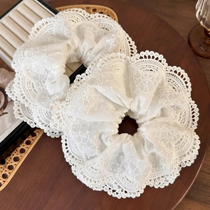 Set di due elastici in pizzo bianco con ricami floreali su vassoio di legno elegante