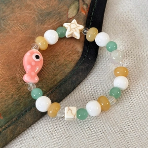 Dettaglio del braccialetto fatto a mano con pesciolino rosa e perline di ceramica verde