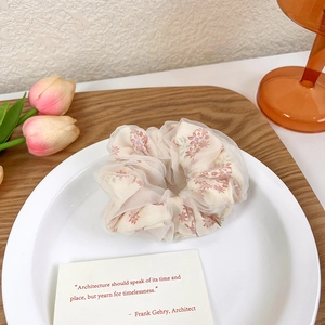 Détail d'un chouchou en tulle fleuri posé sur une assiette avec décor de tulipes