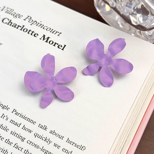 Primo piano di orecchini a fiore viola opaco su un libro per un look estetico e dolce