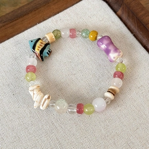 Dettaglio di perline di pesce in ceramica colorata e pietre su bracciale artigianale