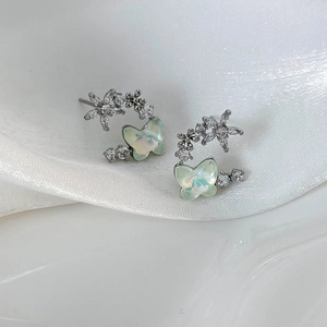 Macro shot of silver butterfly earrings with colorful shells and sparkling zircon stones