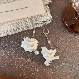 Detailed macro view of long drop earrings with white resin petals and pearls