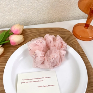 Détail d'un chouchou en organza rose avec imprimé floral délicat sur une assiette