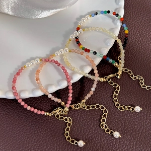 Detail of four colorful beaded bracelets with crystals and pearls on white ceramic