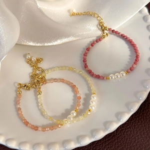 Detailed macro view of colorful stone beaded bracelet with three central pearls and gold clasp