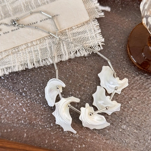 Detailed shot of silver shell necklace with five iridescent pendants on beige linen