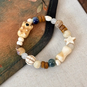 Dettaglio del bracciale con perline, orsetto in ceramica gialla e ciondolo stella
