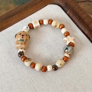 Dettaglio di bracciale con ciondolo a forma di cane in ceramica e perle di legno