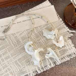 Detailed macro view of sea shell necklace with silver bead chain and white pearl pendants