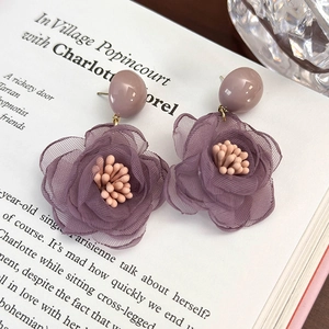 Dettaglio di orecchini a fiore in tessuto viola con petali in rete e stami rosa