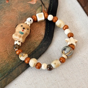 Dettaglio di un bracciale fatto a mano con perline, ciondolo a cane e legno
