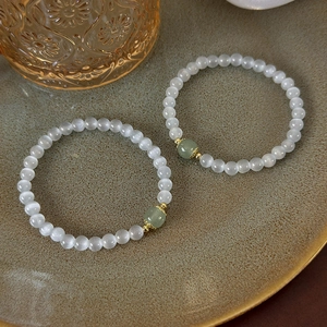 Bracelet minimaliste en pierre œil de chat avec perle de jade vert sur un plateau