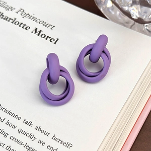 Dettaglio di orecchini geometrici viola opachi su un libro con accenti in vetro
