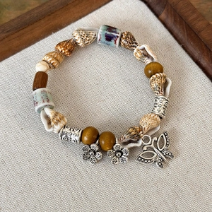 Vista dettagliata del bracciale boho con perle di ceramica, conchiglie e ciondoli a fiore