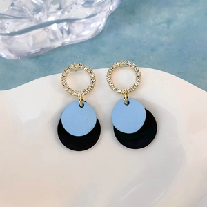 Dettaglio di orecchini a disco blu e nero con montatura in zirconi placcati oro