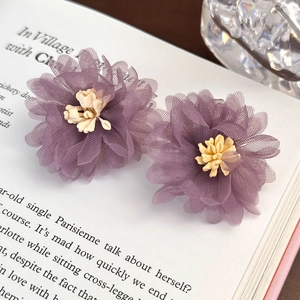 Macro di fermagli per capelli a fiore in tulle viola con stami gialli su libro vintage