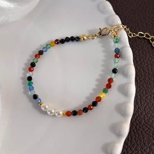 Close-up of multicolor beaded bracelet with white pearls and gold adjustable clasp