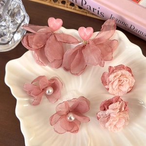 Boucles d'oreilles fleurs en mousseline rose et pétales de cœur sur plateau coquille
