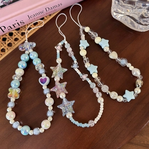 Three beaded phone charms with sea salt blue stars and pearls on a dark wood table